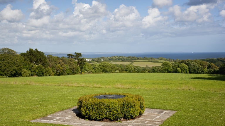 A slate viewfinder surrounded by box hedging, with sweeping views across fields to the sea beyond.